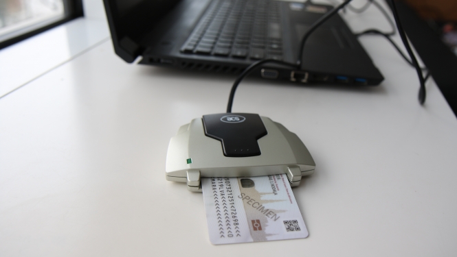 E-parakstītājs ar eID karti, blakus portatīvajam datoram