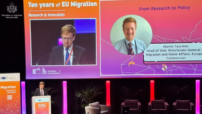 Fotoattēls no konferences, Uz skatuves uzstājas ar runu vīrietis.