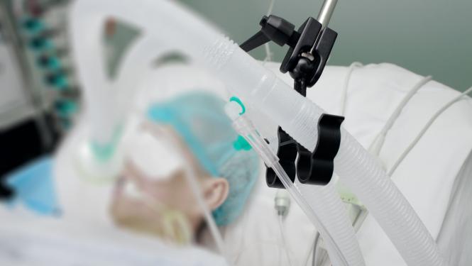 Slimnieks guļ slimnīcā ar plaušu ventilācijas aparātu