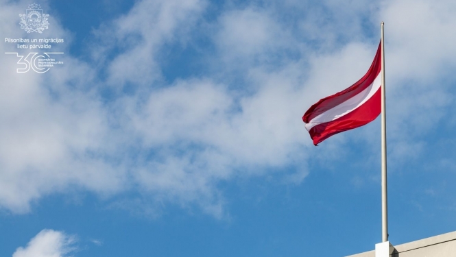 Latvijas karogs, kas plīvo zilajās debesīs 