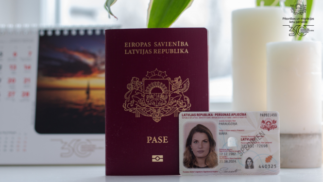 Uz galda stāv pase,eID karte, un galda kalendārs ar saulrietu