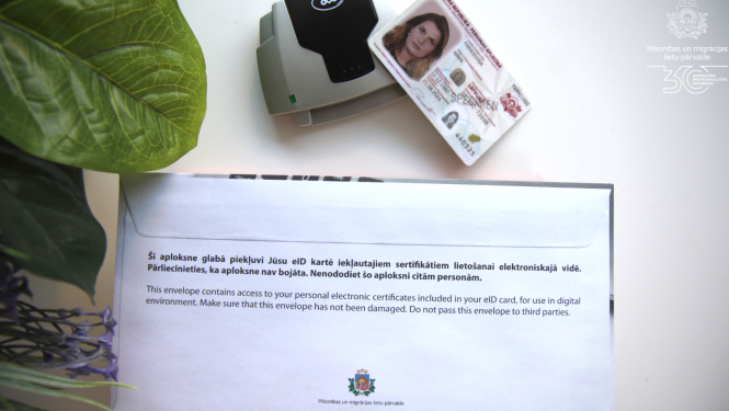 eID karte uz galda ar PIn aploksni un viedkartes lasītāju