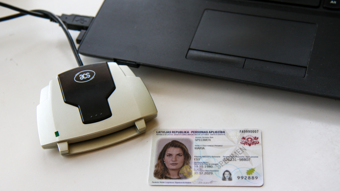 Ārzemnieka eID karte ar e-paraktītāju, blakus portatīvajam datoram