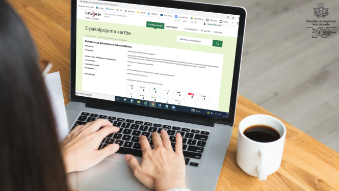 Datorā atvērts jauns Deklarēšanās e-pakalpojums , uz galda - kafijas krūze