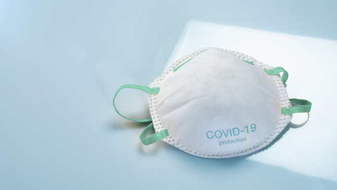 Mutes un deguna aizsegs baltā krāsā ar zaļām gumijām, uz galda