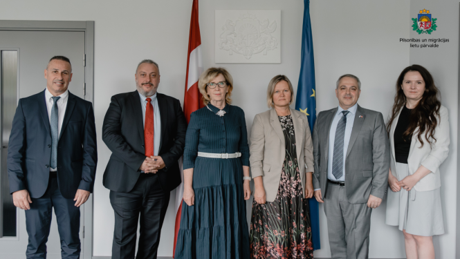 Pārvaldes pārstāvji stāv blakus Izraēlas delegācijas pārstāvjiem. Fonā - Latvijas karogs.