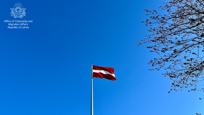 Latvijas karogs uz zilo debesu fona