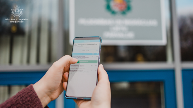 Cilvēka roka ar mobilo telefonu, kur ir "atvērta" Qticket mobila lietotne