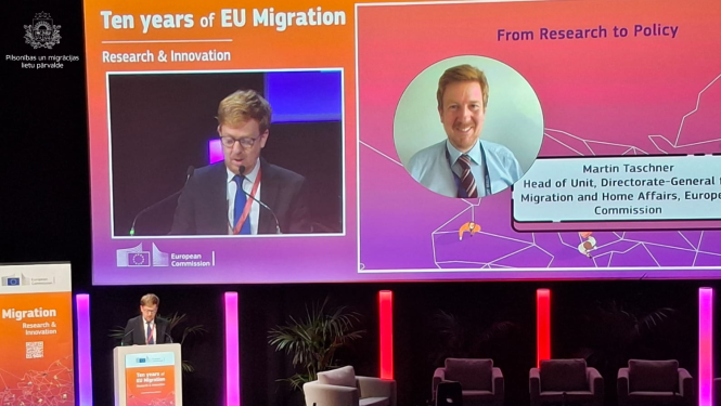 Fotoattēls no konferences, Uz skatuves uzstājas ar runu vīrietis.