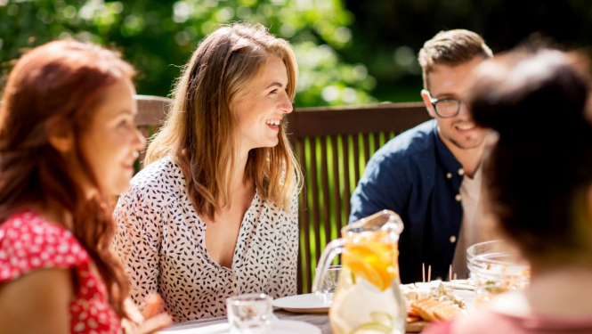 Priecīgi cilvēki sēž pie galda