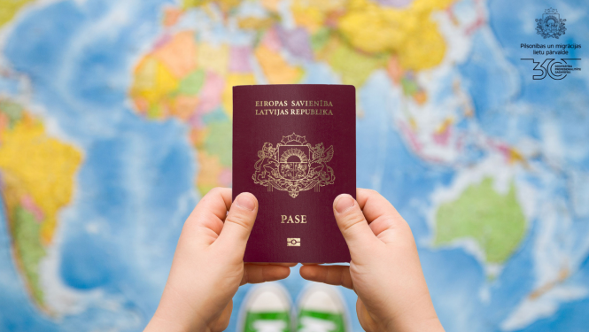 Bērna rokas, kas tur pasi uz pasaules kartes fona