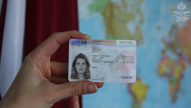 uzturēšanas atļaujas karte uz kartes un Latvijas karoga fona