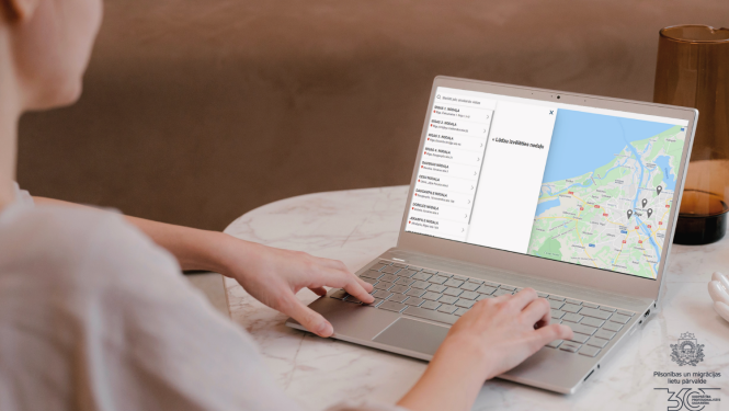 Sievietes aizmugure, sēžot pie datora un ar atvērtu Qticket programmu