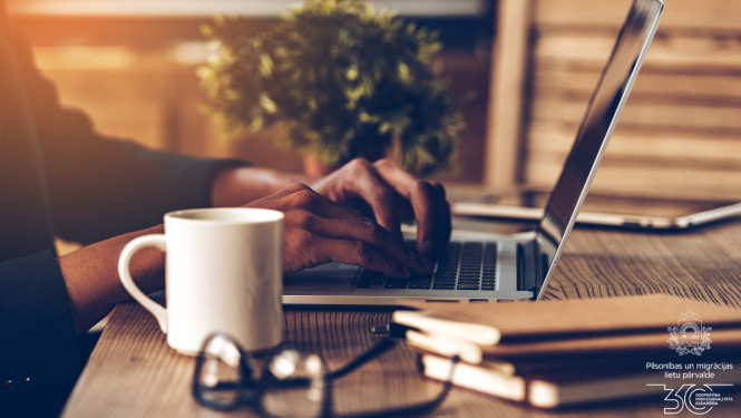 Uz galda: krūze, brilles, burtnīcas