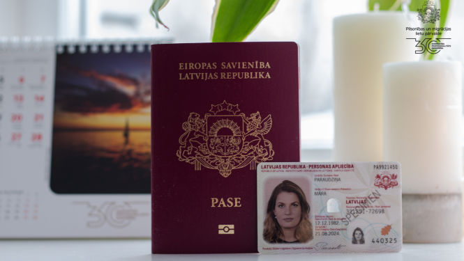 Uz galda stāv pase,eID karte, un galda kalendārs ar saulrietu