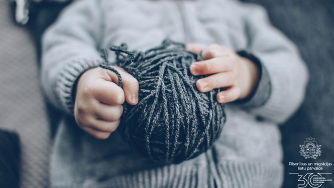 Bērna rokas, kas tur adīšanas vītni