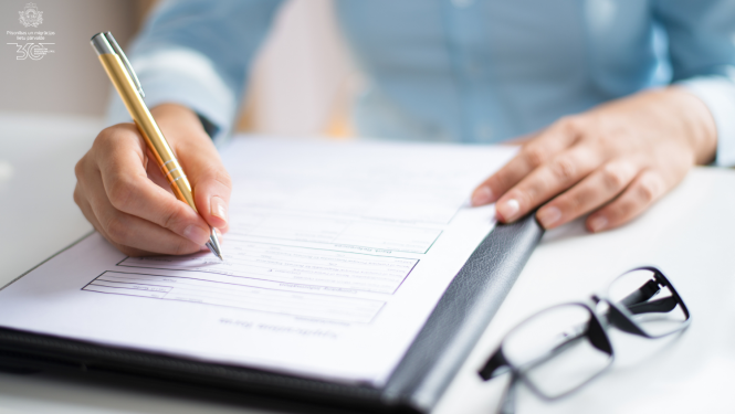 Cilvēka roka raksta uz papīra, blakus uz galda - brilles