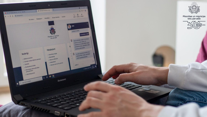 CIlvēka rokas, kas strādā pie datora, datorā atvērta Pārvaldes mājaslapa