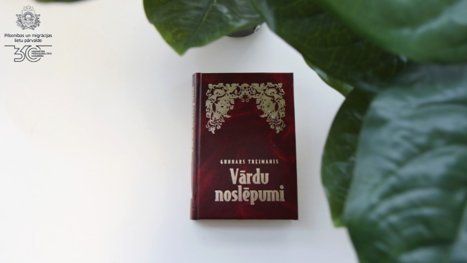 Grāmata uz galda "Vārdu noslēpumi" tumši sarkanajos vākos