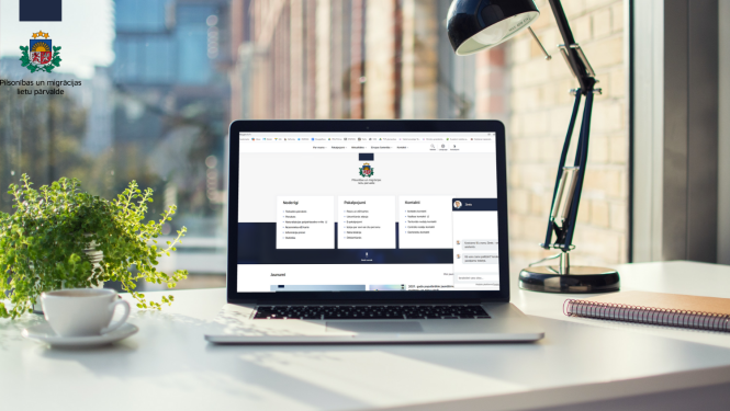 uz galda stāv dators ar atvērtu pmlp mājaslapu