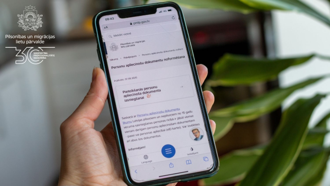 Cilvēka rokā mobilais telefons ar atvērtu Pārvaldes mājaslapu