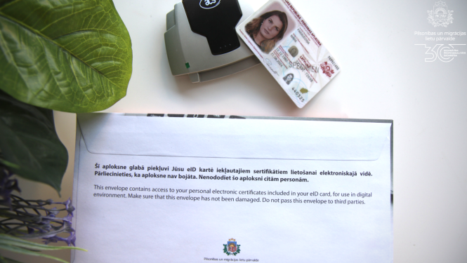 eID karte uz galda ar PIn aploksni un viedkartes lasītāju