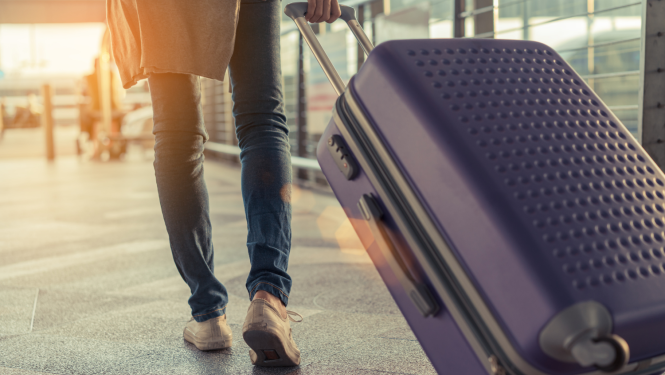 Cilvēka kājas un ceļojuma koferis