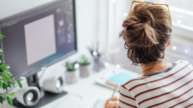 Fotogrāfija sievietes no mugurpuses, sēž pie datora