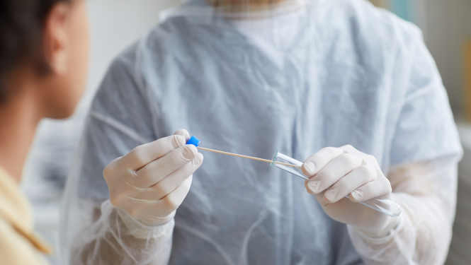 Cilvēks medicīniskajā formā ņem testu uz Covid-19