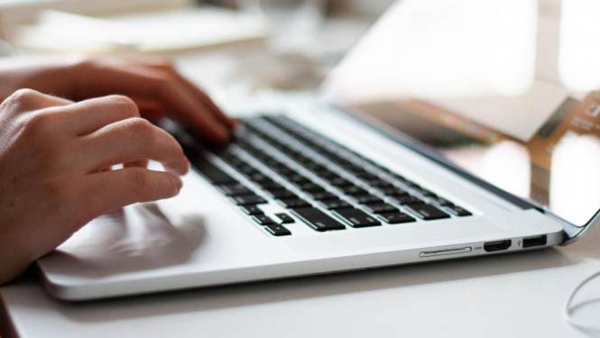 Cilvēka rokas, strādājot pie portatīvā datora