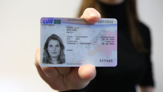 Uzturēšanas atļaujas karte sievietes rokā.