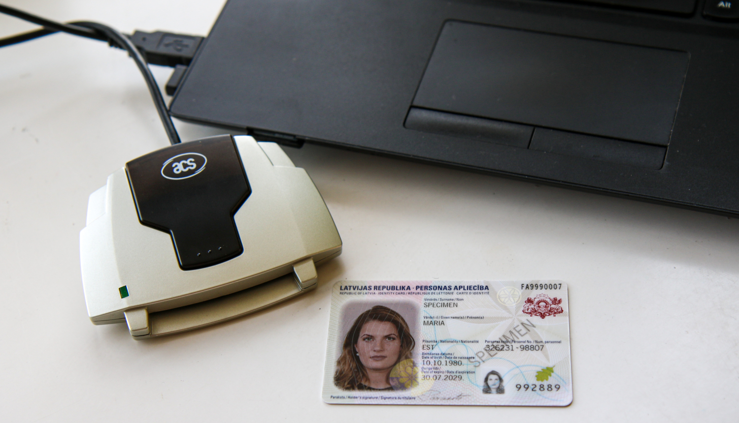 Ārzemnieka eID karte ar e-paraktītāju, blakus portatīvajam datoram