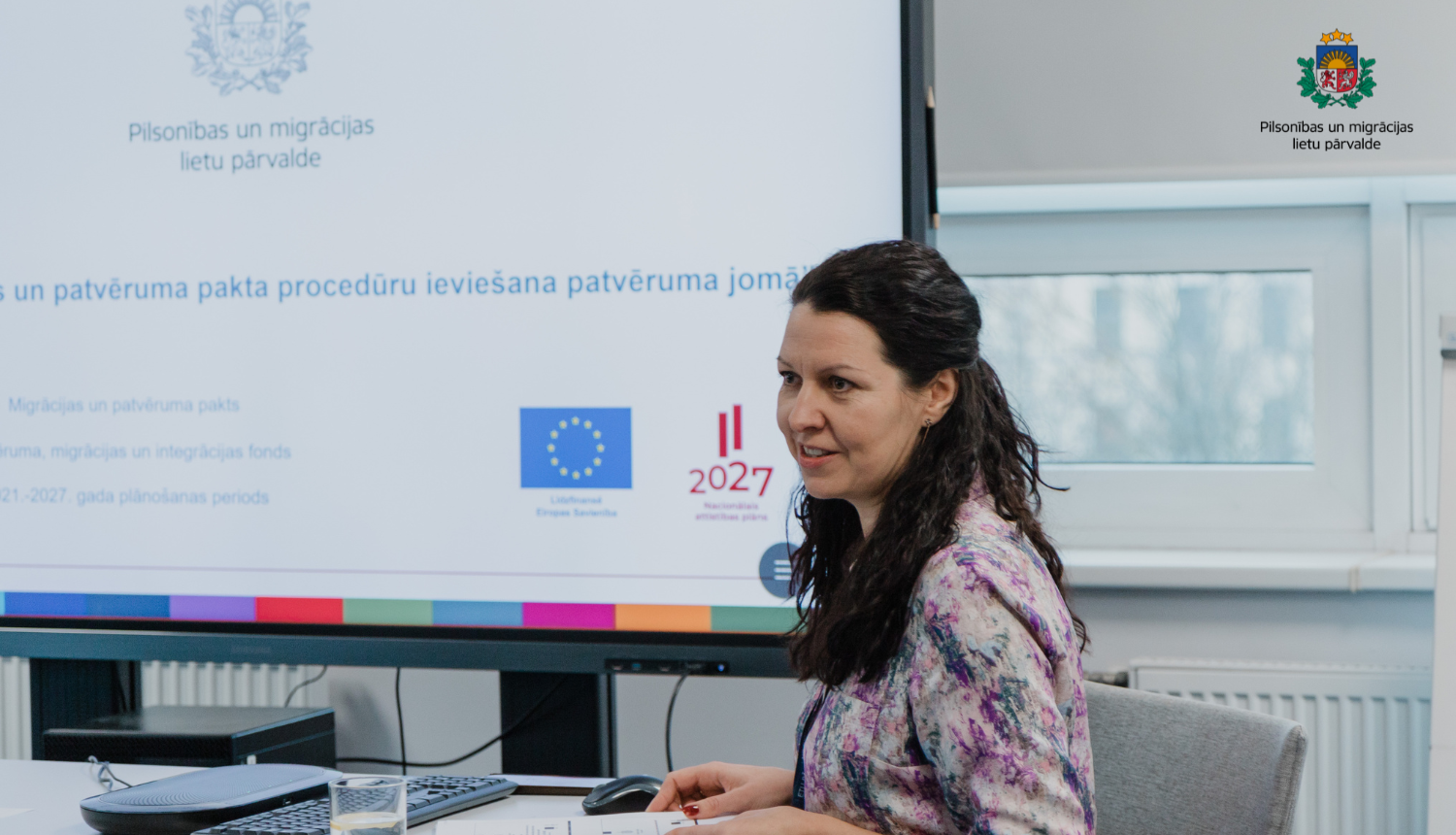 ES projekta vadītāja sēž pie galda, un prezentē projektu