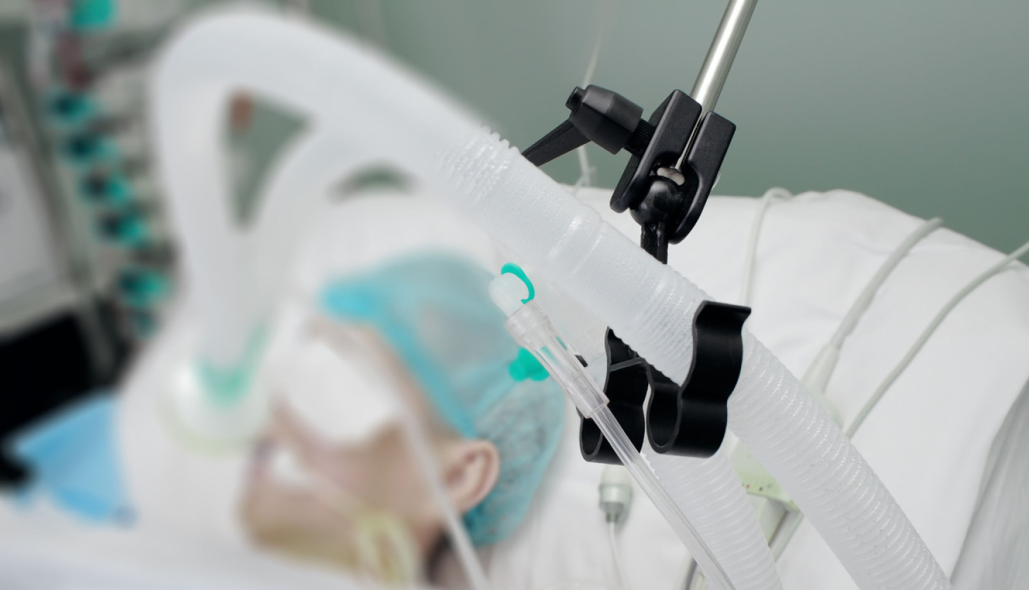 Slimnieks guļ slimnīcā ar plaušu ventilācijas aparātu