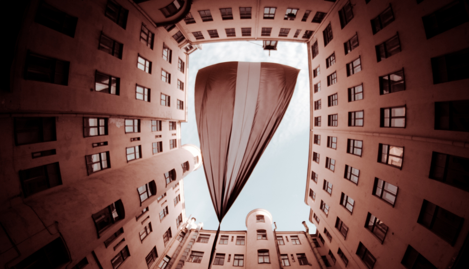 Plīvojošs Latvijas karogs starp ēkām