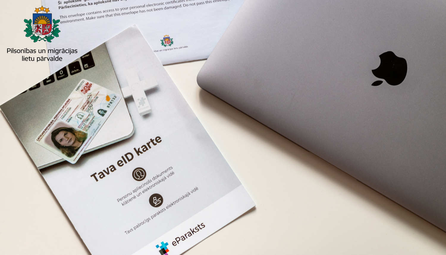 Uz galda stāv brošūra par eID karti, portatīvais dators