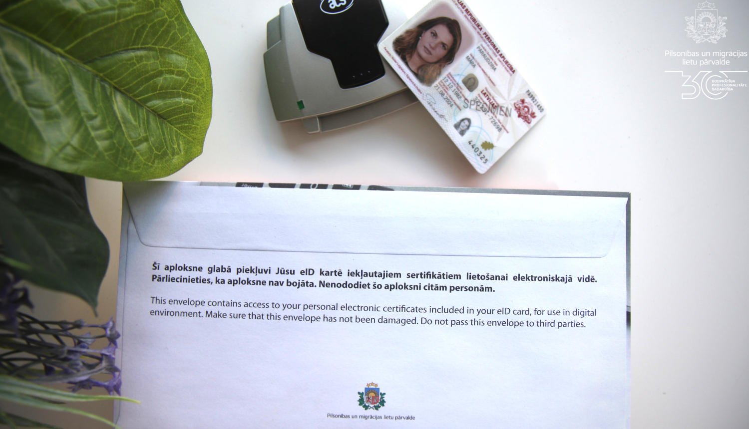 eID karte uz galda ar PIn aploksni un viedkartes lasītāju