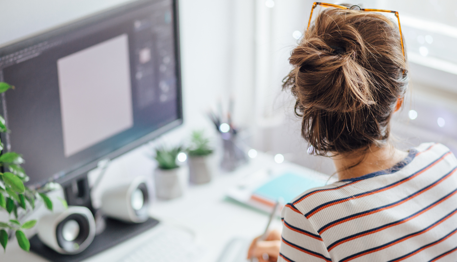 Fotogrāfija sievietes no mugurpuses, sēž pie datora