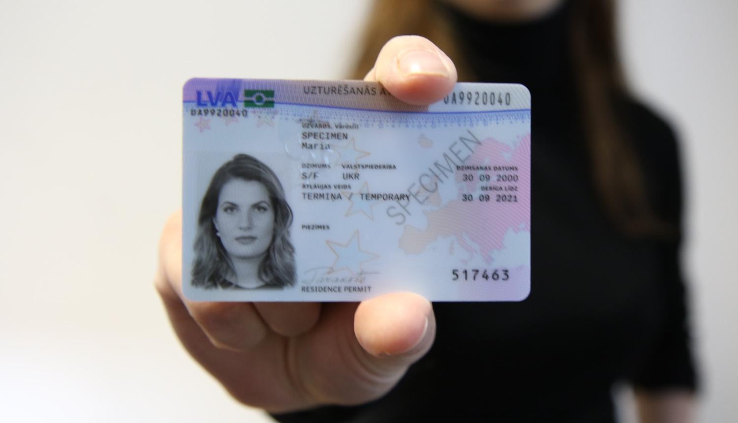 Uzturēšanas atļaujas karte sievietes rokā.