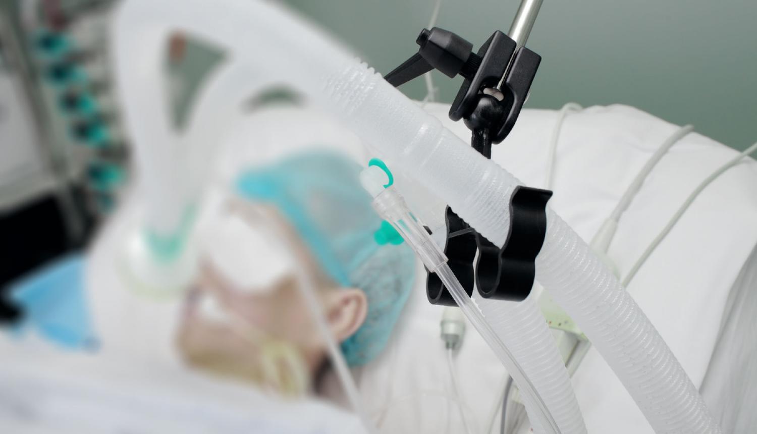 Slimnieks guļ slimnīcā ar plaušu ventilācijas aparātu