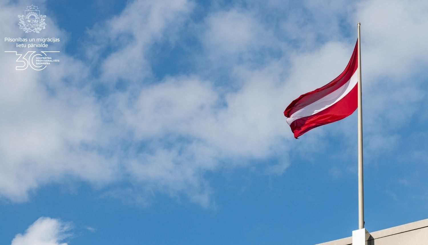 Latvijas karogs, kas plīvo zilajās debesīs 
