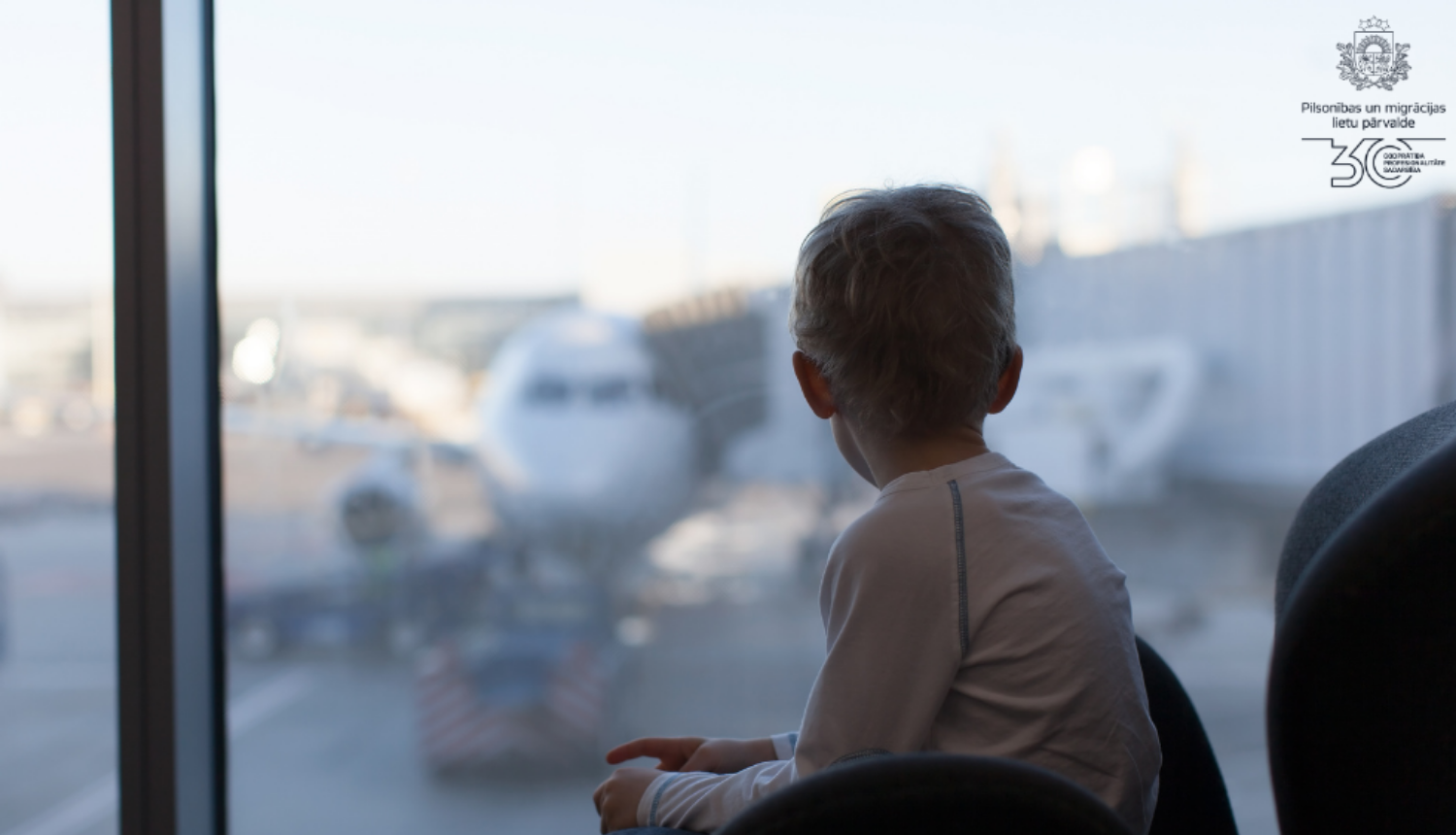 Bērns skatās pa logu lidostā