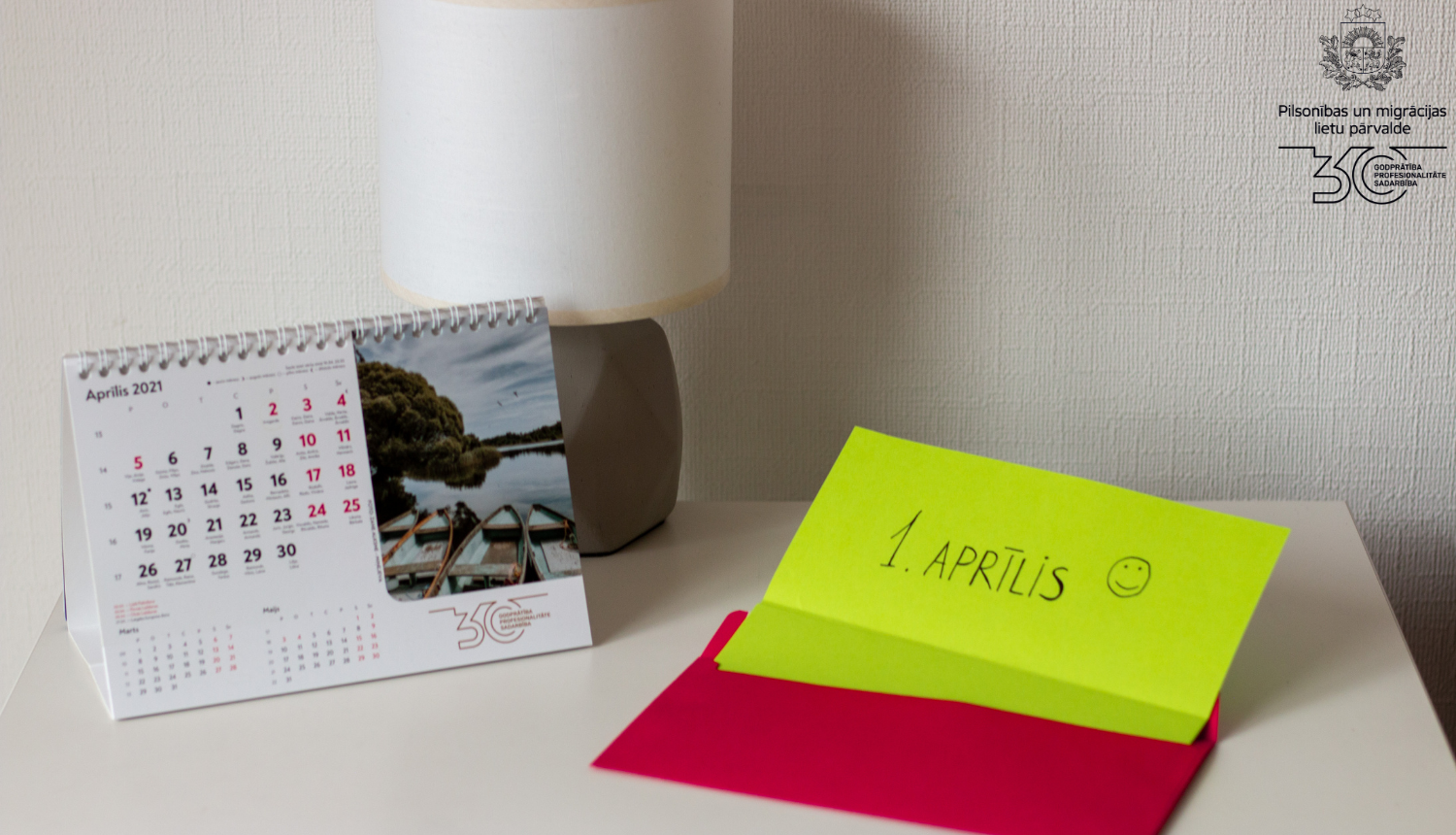 Kompoz'icija uz galda: galda kalendārs un līmlapiņā spilgti dzeltenā kr;as;a ar uzrakstu "1. aprīli :)"