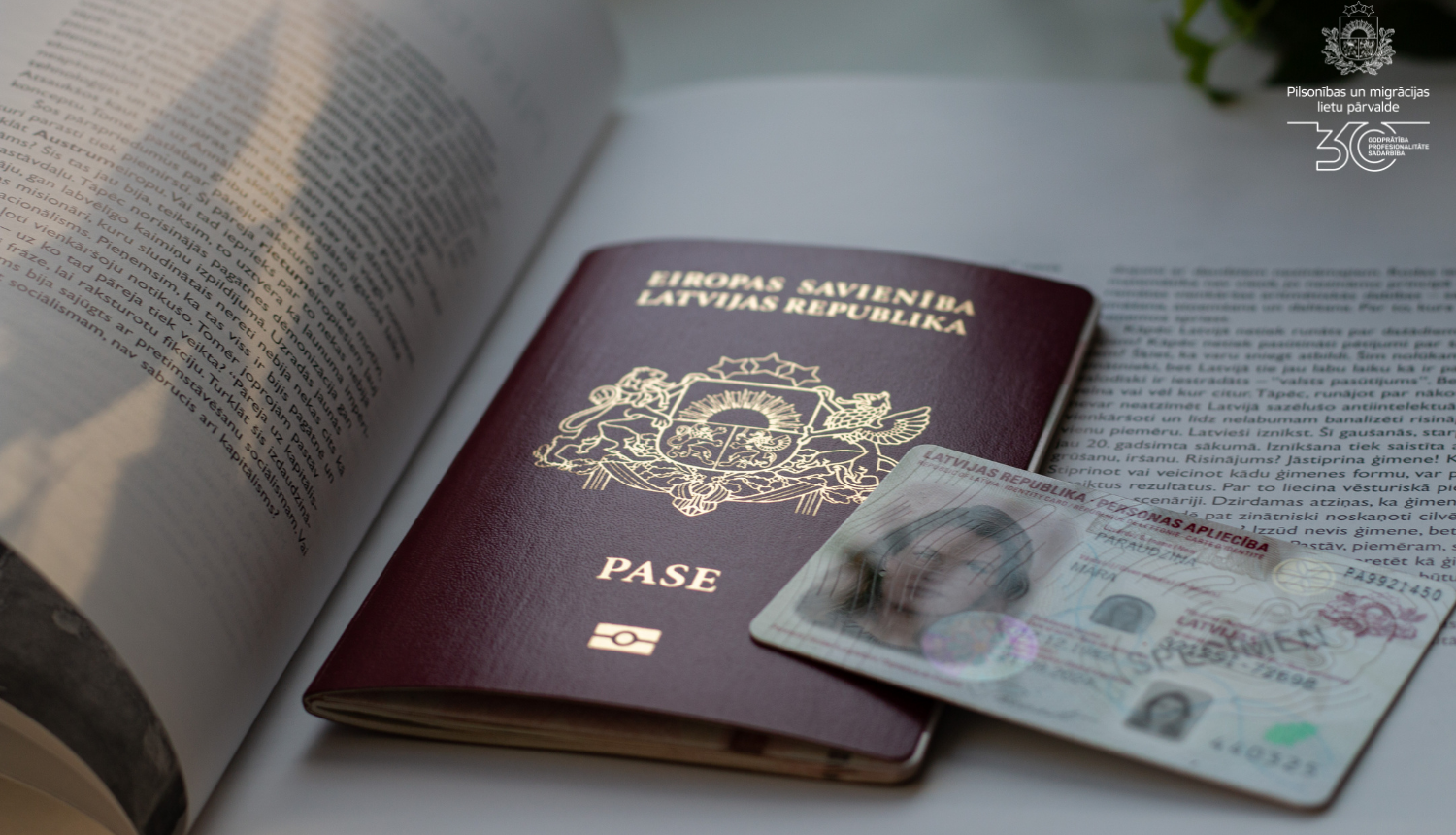 Uz atvērtas grāmatas ir Latvijas pilsoņa pase un eID karte