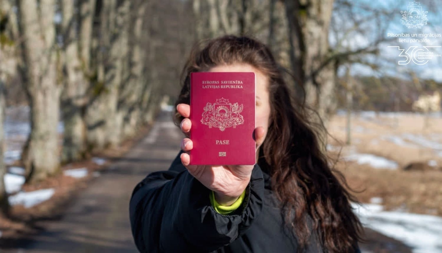 Sieviete tur pasi izstieptā rokā, aizsedzot seju ar to