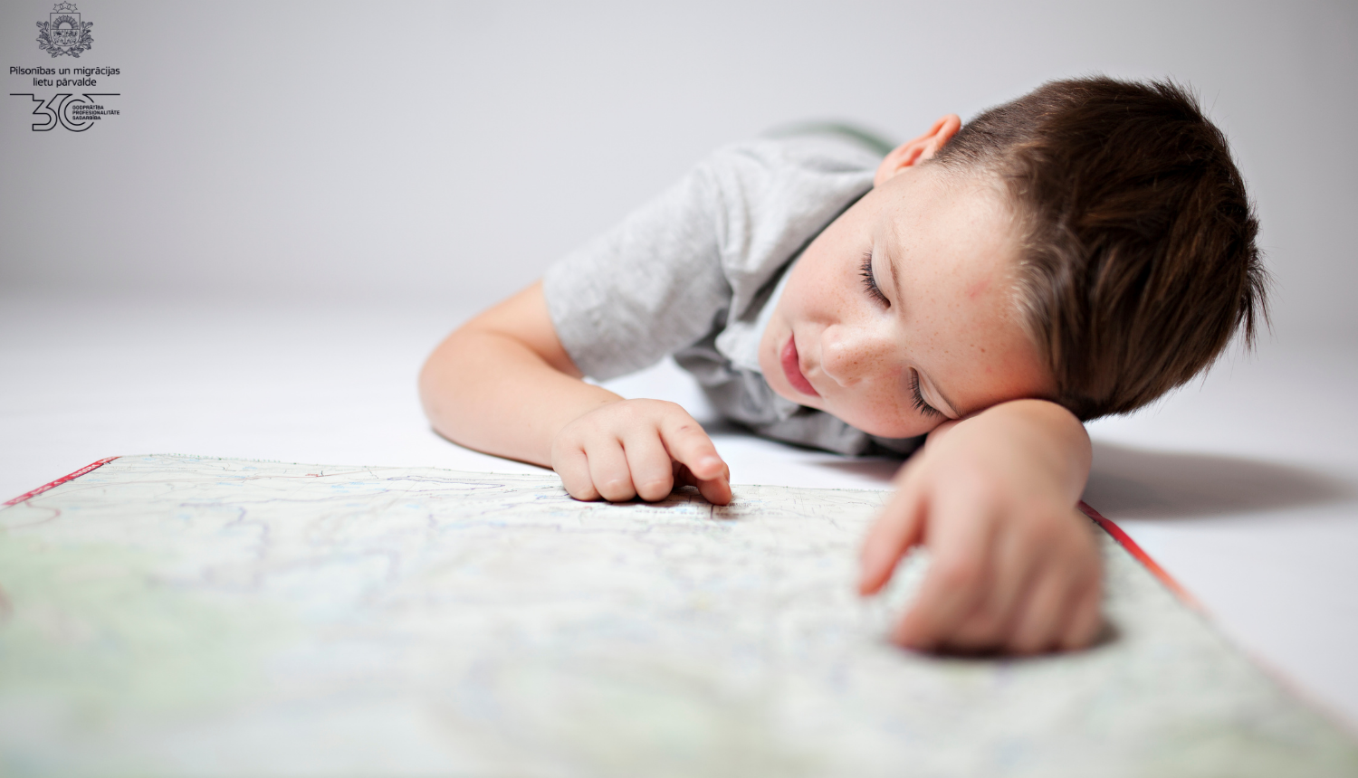 Mazs zēns uz grīdas skatās karti