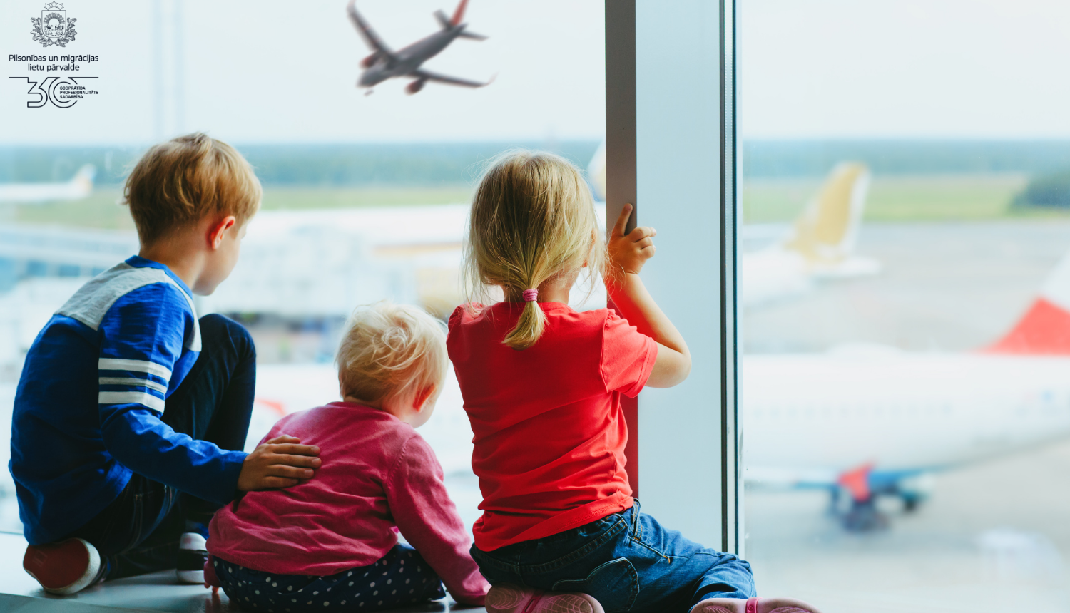 bērni lidostā skatās uz aizlidojošu lidmašīnu